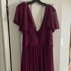 a purple dress hanging on a door with a hanger in front of it that has an open back