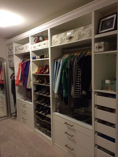 an organized closet with white drawers and lots of clothes