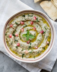 a white bowl filled with hummus and garnish next to pita chips