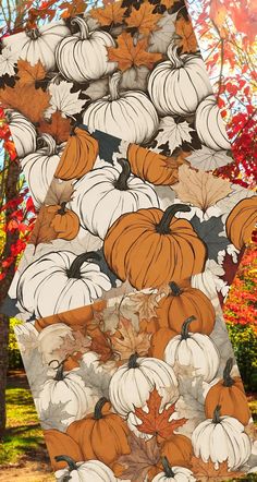 a large number of pumpkins and leaves on a table in front of some trees