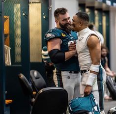 two football players embracing each other in the locker room