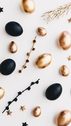 some gold and black eggs on a white surface with stars, pine needles and sprigs