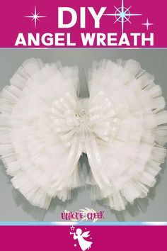 an angel wreath with white tulle and stars on the top, in front of a pink background