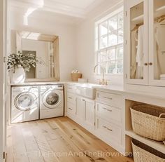 a washer and dryer in a white laundry room with wood flooring, large windows, and wicker baskets