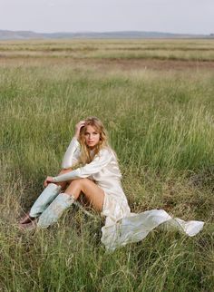 a woman is sitting in the tall grass