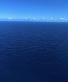 the ocean is very blue and clear with some clouds in the sky on top of it