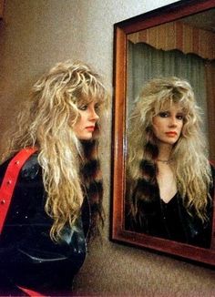 a woman with long blonde hair standing in front of a mirror