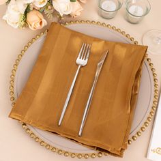 a place setting with silverware, napkins and flowers on a tablecloth that has gold beaded edges