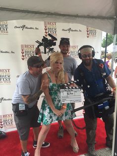 a group of people standing next to each other on a red carpet with a camera