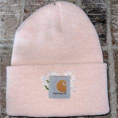 a pink beanie sitting on top of a brick wall