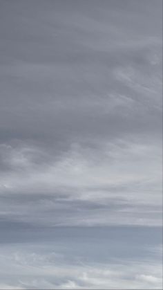 an airplane is flying in the sky with clouds above it and another plane on the ground