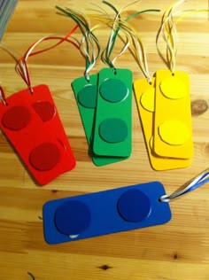 four lego tags on a wooden table with scissors and string attached to the tags that are shaped like legos