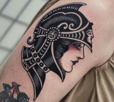 a woman's shoulder with a black and white tattoo design on her left arm