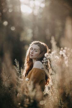 a woman standing in tall grass looking off into the distance