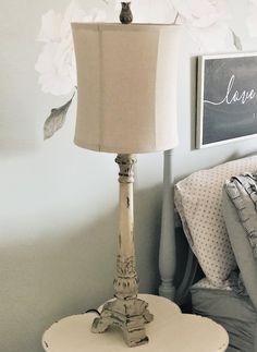 a white lamp sitting on top of a table next to a bed