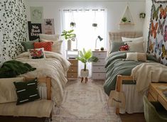 two beds in a room with plants on the wall and curtains hanging from the windows