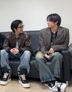 three people sitting on a couch talking to each other in front of a white wall