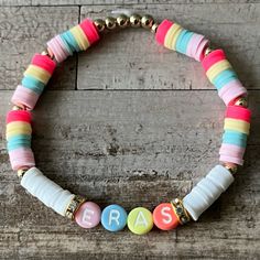 a beaded bracelet with the word eras spelled out in multicolored beads on a wooden surface