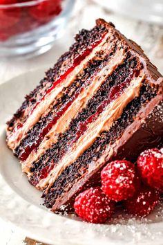 a large piece of chocolate cake with raspberries on the side and one slice missing