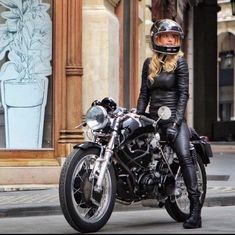 a woman sitting on top of a black motorcycle