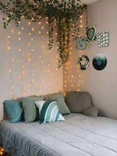 a bed sitting under a tree with lights on the wall above it and pillows below