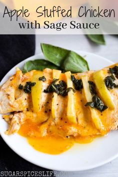 an apple stuffed chicken with sage sauce on a white plate next to spinach leaves