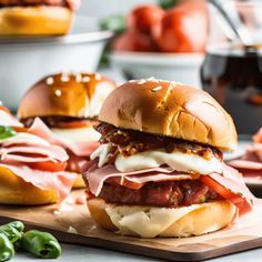 three sandwiches with meat, cheese and sauces on a cutting board next to green peppers