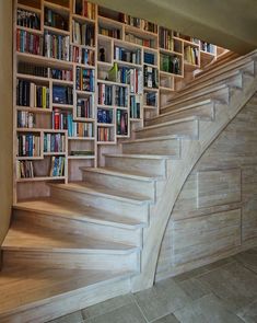 there is a book shelf with many books on it and stairs leading up to the second floor