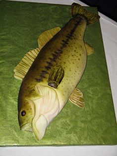 a cake shaped like a fish sitting on top of a green tablecloth covered in white frosting