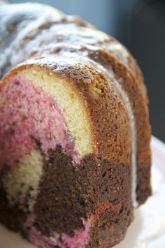 a close up of a bundt cake on a white plate with pink and brown frosting