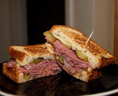 a cut in half sandwich sitting on top of a black plate with toothpicks