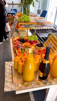 an assortment of fruits and juices on a buffet table with people in the background