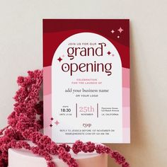 a pink and white cake with red sprinkles on it next to a card that says grand opening