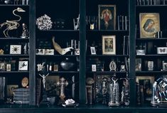 a black bookcase filled with lots of books next to pictures and vases on top of it