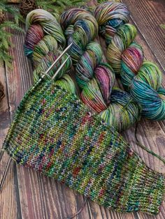 a skein of yarn sitting on top of a wooden floor next to a pair of knitting needles