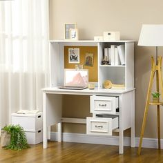 a white desk with two drawers and a lamp on the floor in front of a window