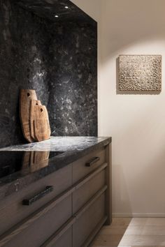 a wooden cutting board sitting on top of a counter next to a wall mounted oven