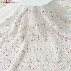 a white crochet tablecloth with brown dots on it and a pink flower in the background