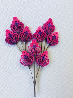 several pink and purple flowers on a white surface with one flower shaped like a heart