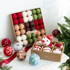 an assortment of christmas ornaments in boxes on a table next to a small christmas tree