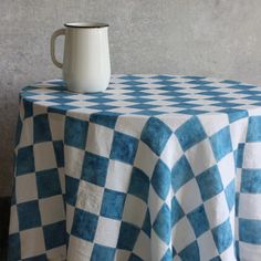 a blue and white checkered table cloth with a coffee cup on top