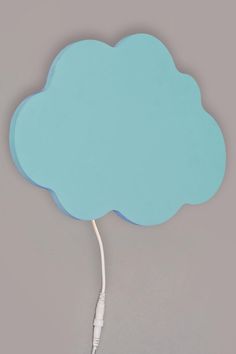 a blue cloud shaped object is plugged in to a white cord on a gray background