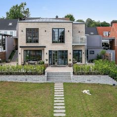 a house with stairs leading up to the front door and lawn area in front of it