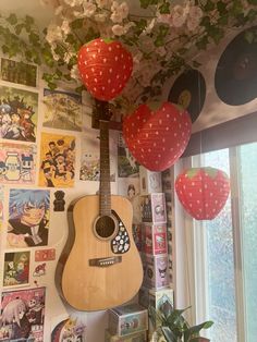 a guitar hanging from the ceiling in front of a wall with pictures and balloons on it