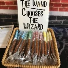 a basket filled with lots of different types of candy in plastic wrappers next to a sign that says, the wand chooses the wizard