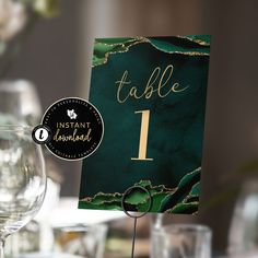 a table number sitting on top of a card next to some wine glasses and silverware