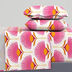 three pillows are stacked on top of each other in front of a gray background with pink and orange designs