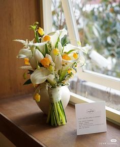 a bouquet of flowers sitting on top of a window sill next to a card