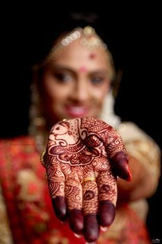 a woman holding her hand up to show the henna