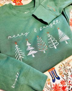 "Elevated your holiday wardrobe with embroidered sweatshirt! Embroidered minimalist Christmas Trees on front chest of the shirt, left wrist is embroidered with the word \"merry\", right wrist is embroidered with the word \"bright\".  Perfect for gifting, family matching, or holiday party. --------------------------------------------------------------------------------------------------------------------------------------- Rock a classic sweatshirt silhouette with ribbed crew neck, long sleeve cu Xmas Party Outfits, Sweatshirt Embroidery, Minimalist Christmas Tree, Embroidered Christmas, Embroidery Christmas, Christmas Tree Shirt, Matching Sweatshirts, Winter Shirts, Etsy Christmas